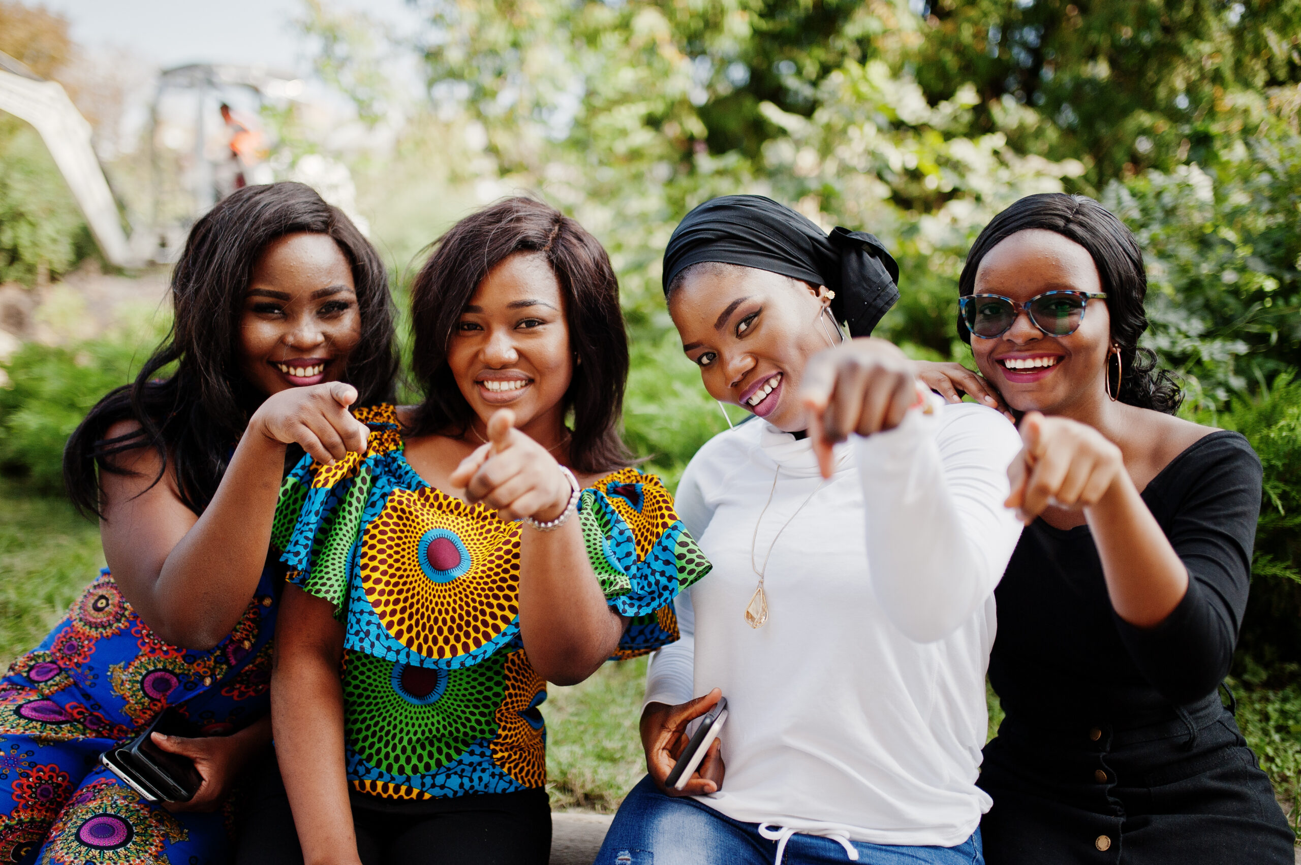 Group of four african american girls sitting outdoor and showing fingers.