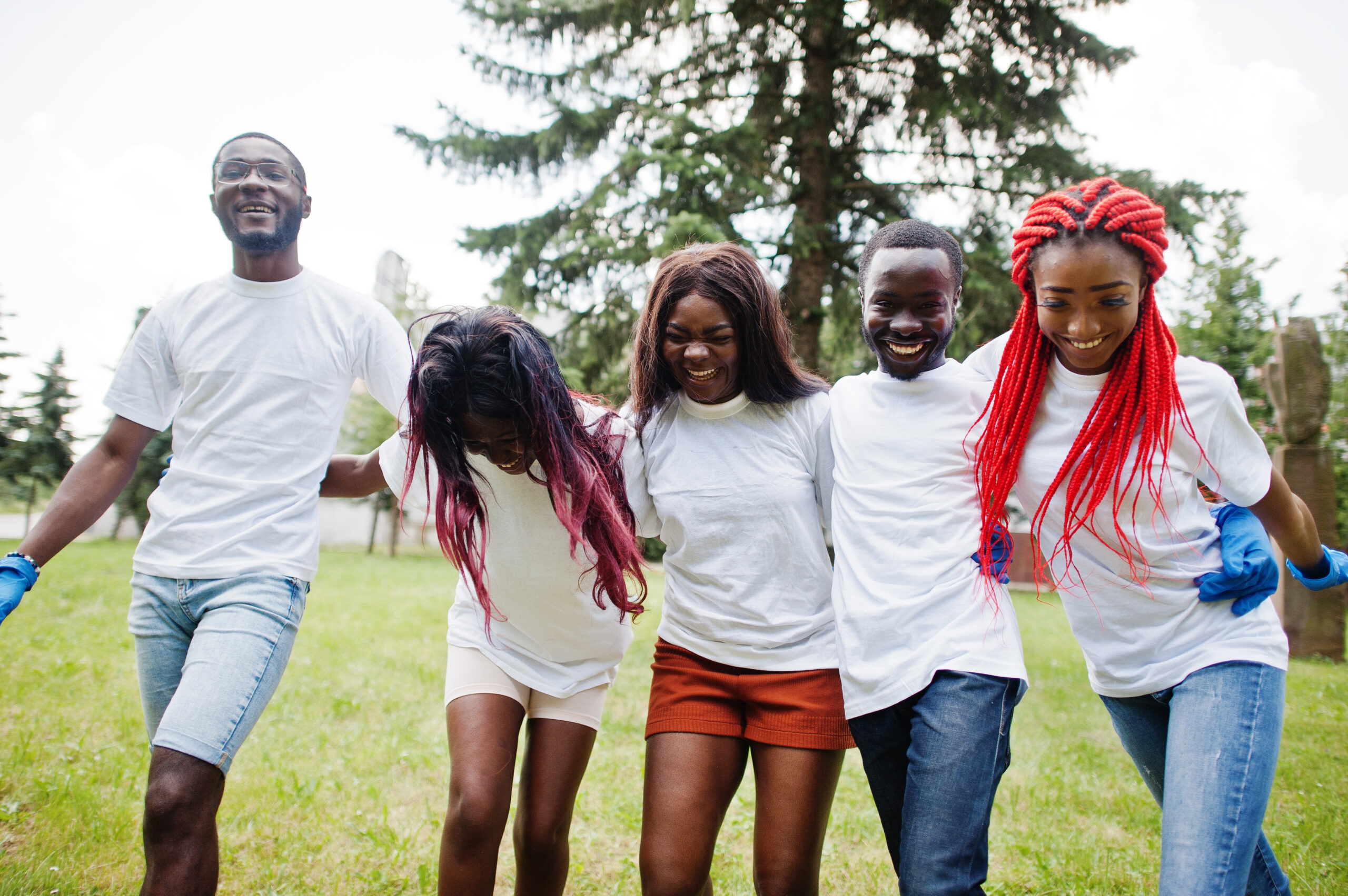 Group happy african volunteers hugs together in park. Africa volunteering, charity, people and ecology concept.